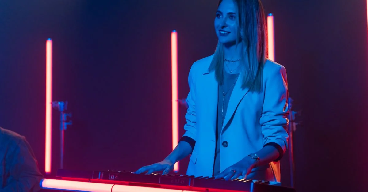 Une musicienne profite de jouer du clavier sous des lumières néon vibrantes dans un cadre moderne.