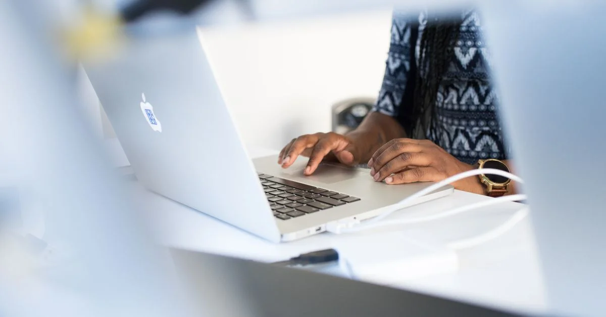 Femme tapant sur un ordinateur portable à un bureau dans un environnement de bureau moderne, concentrée sur son travail.