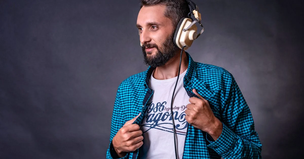 Portrait d'un homme barbu et stylé avec des casques dans un cadre de studio.
