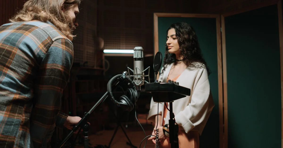 Une femme enregistrant des voix dans un cadre professionnel de studio de musique.