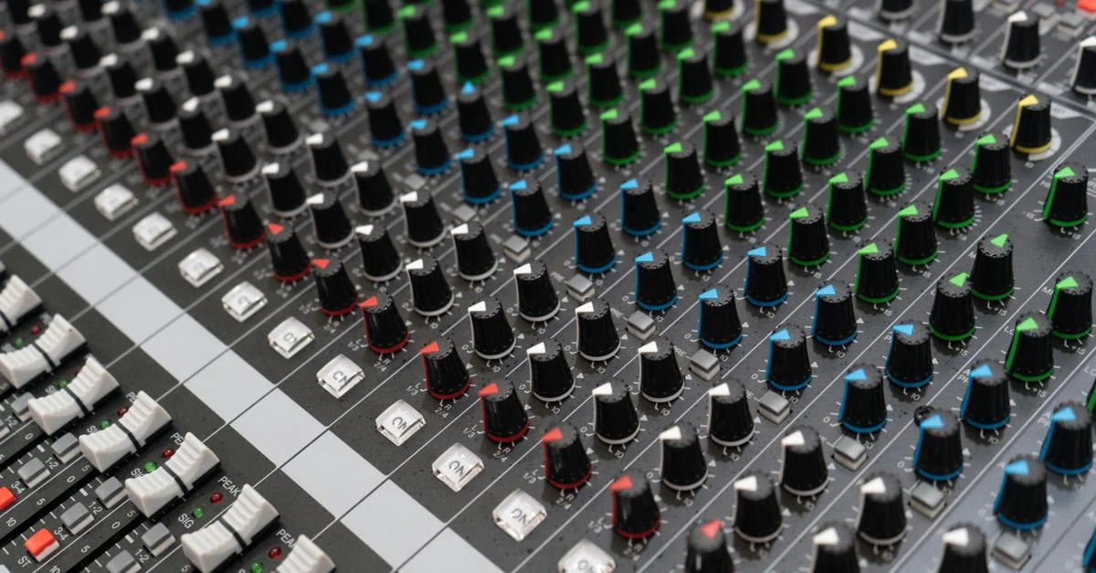 Image détaillée d'un mixeur audio avec des boutons colorés et des commandes dans un environnement de studio.