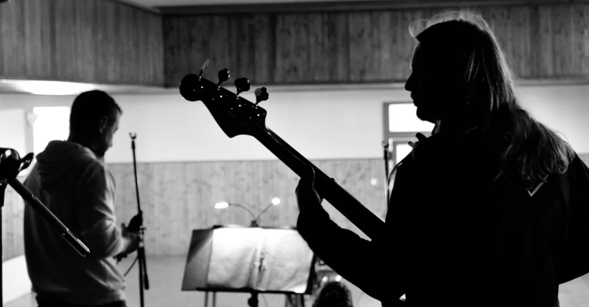 Silhouette de musiciens en répétition avec des instruments dans un cadre en noir et blanc.