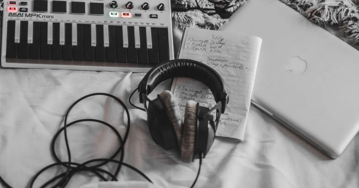 Un ensemble de production musicale confortable avec un contrôleur MIDI, des écouteurs et un ordinateur portable sur une couverture blanche.