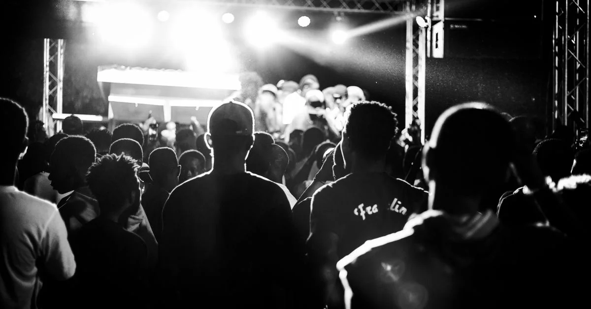 Un cliché dynamique en noir et blanc capturant la foule d'un concert sous de lumineuses lumières de scène.