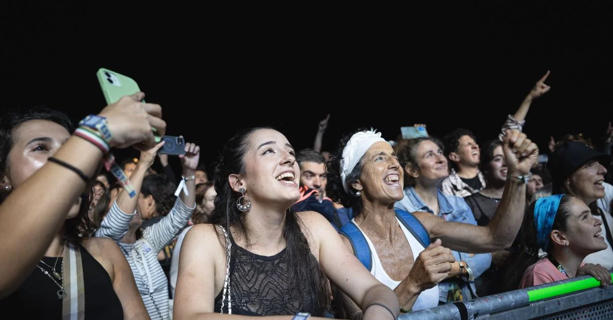 Foule diverse lors d'un concert nocturne. Public montrant excitation et enthousiasme pendant la performance en direct.