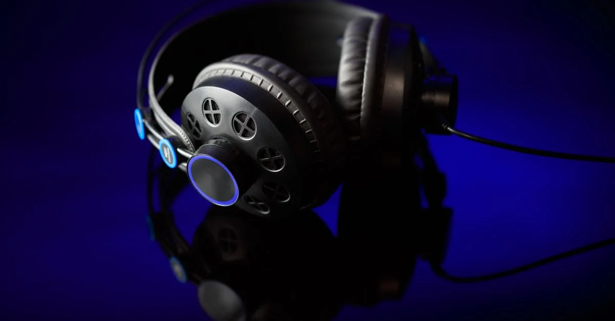 Casque noir élégant avec des accents lumineux sur une surface réfléchissante contre un fond sombre.