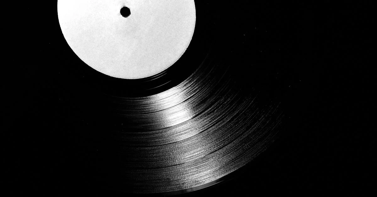 Un gros plan d'un disque vinyle vintage en noir et blanc, mettant en valeur ses rainures.
