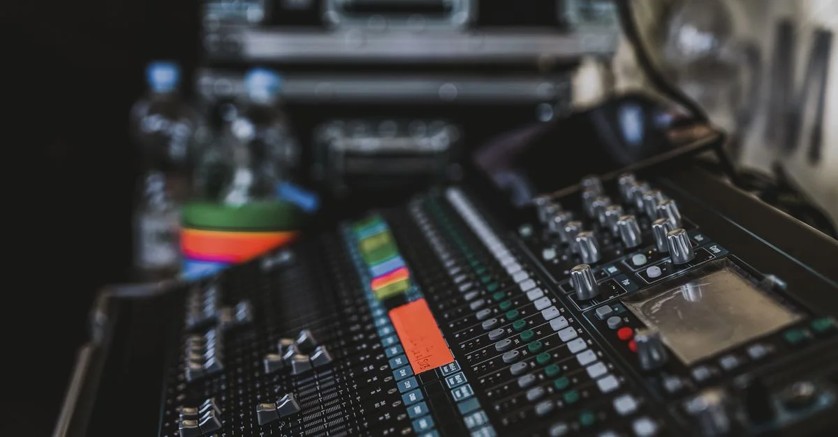 Gros plan sur un mixeur audio professionnel avec divers boutons et faders dans un cadre de studio musical.