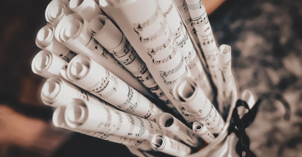 Gros plan artistique de partitions de musique enroulées et liées par un ruban, mettant en valeur l'élégance musicale.