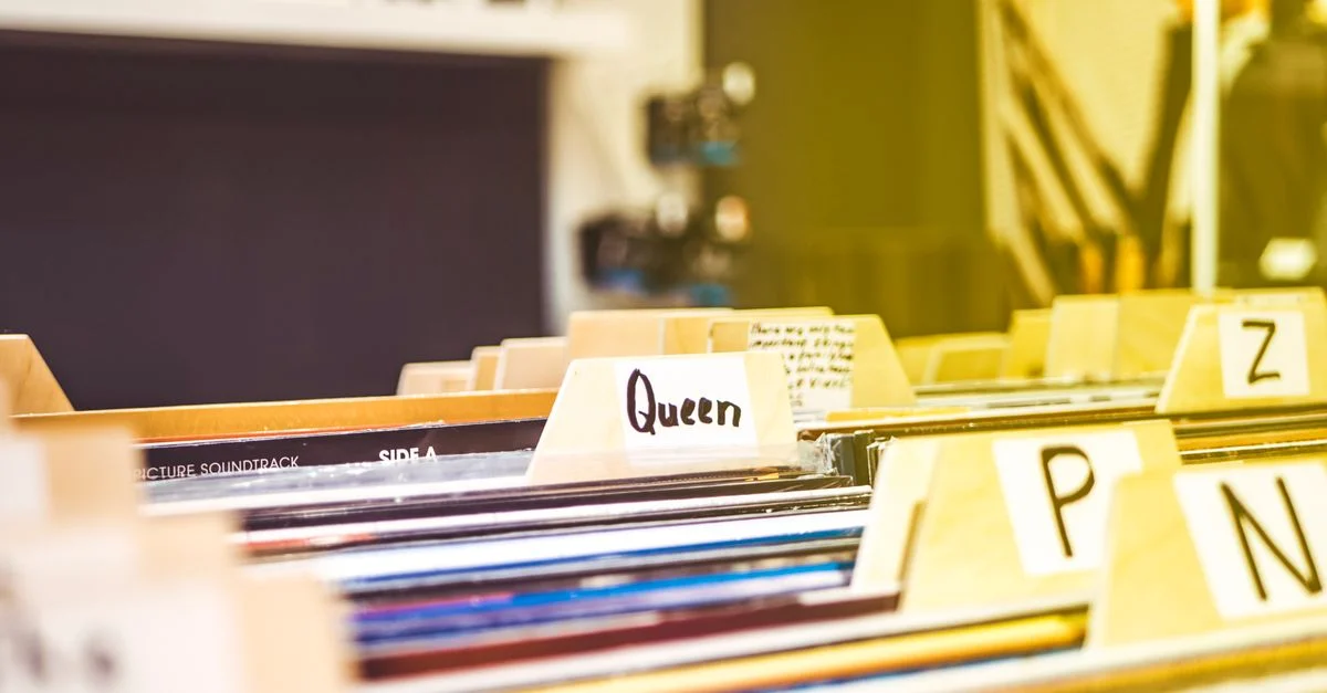 Vue en gros plan de disques vinyles organisés par ordre alphabétique dans un magasin de musique intérieur.