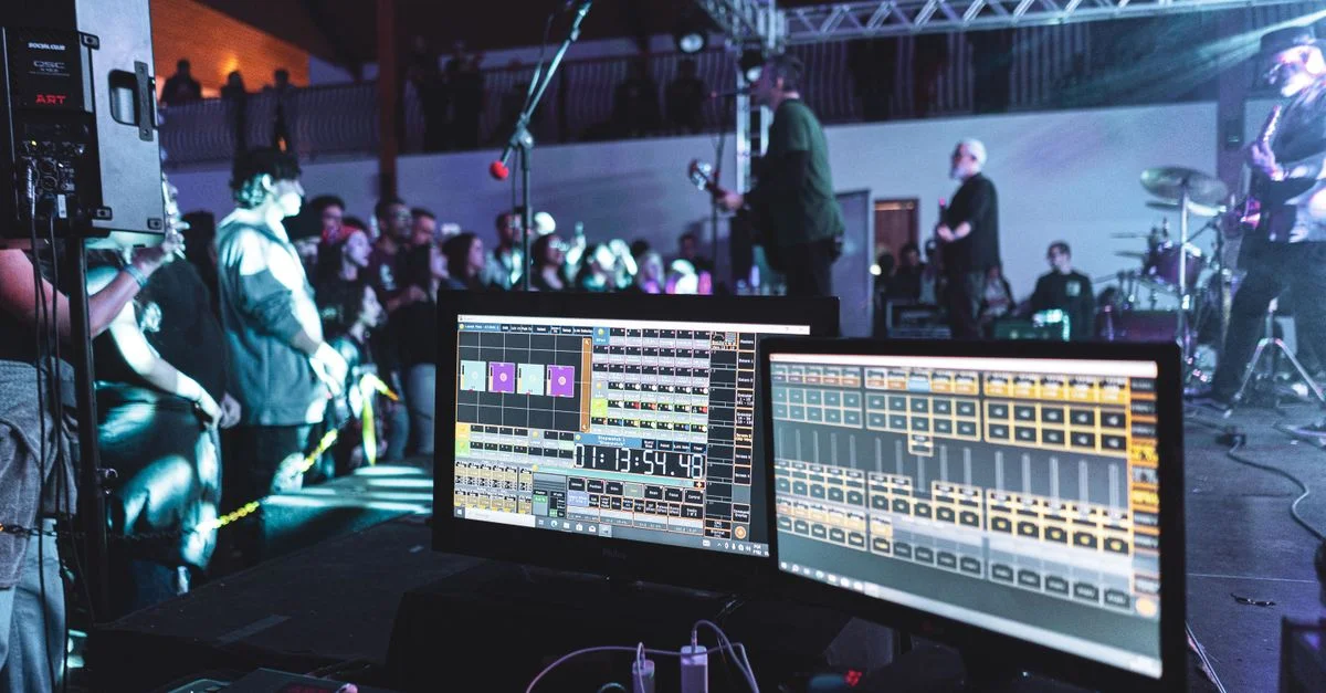 Scène de concert en direct avec installation d'ingénierie du son et groupe sur scène.