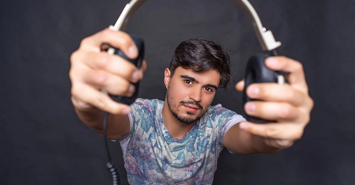 Portrait d'un jeune homme tenant des écouteurs, offrant une vue en gros plan dans un cadre de studio.