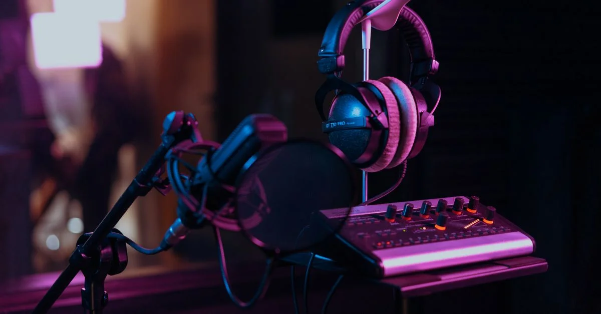 Mise en place d'un studio d'enregistrement audio de haute qualité avec un microphone, des écouteurs et une table de mixage dans un éclairage tamisé.
