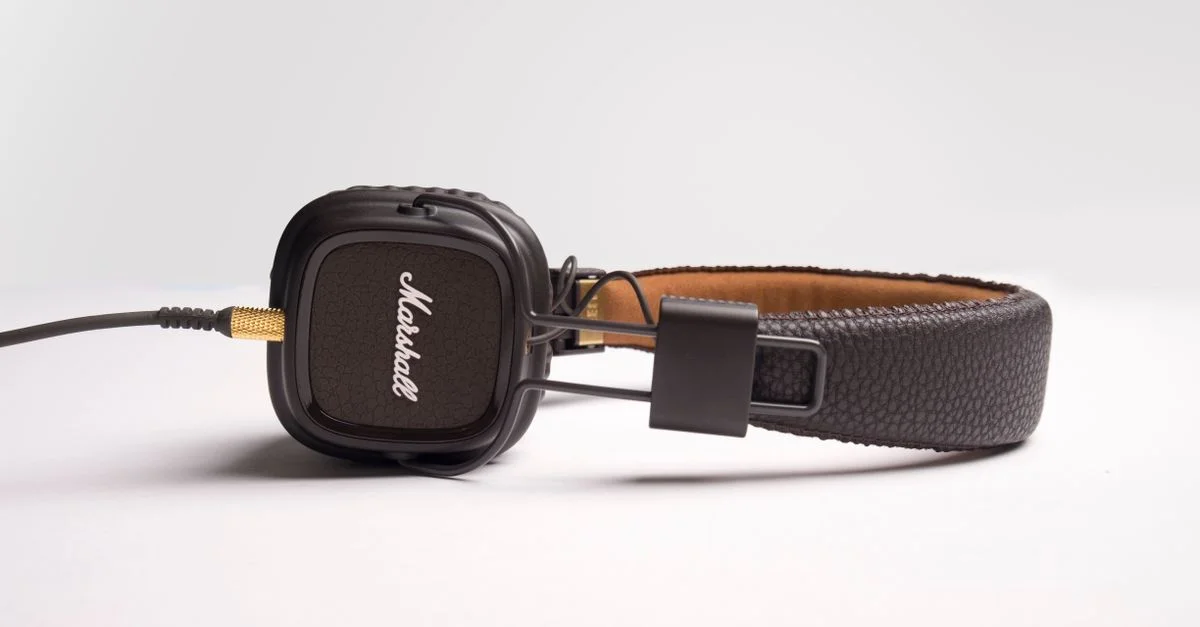 Casque audio circum-aural noir élégant, doté d'un arceau rembourré et d'oreillettes de marque sur fond blanc.