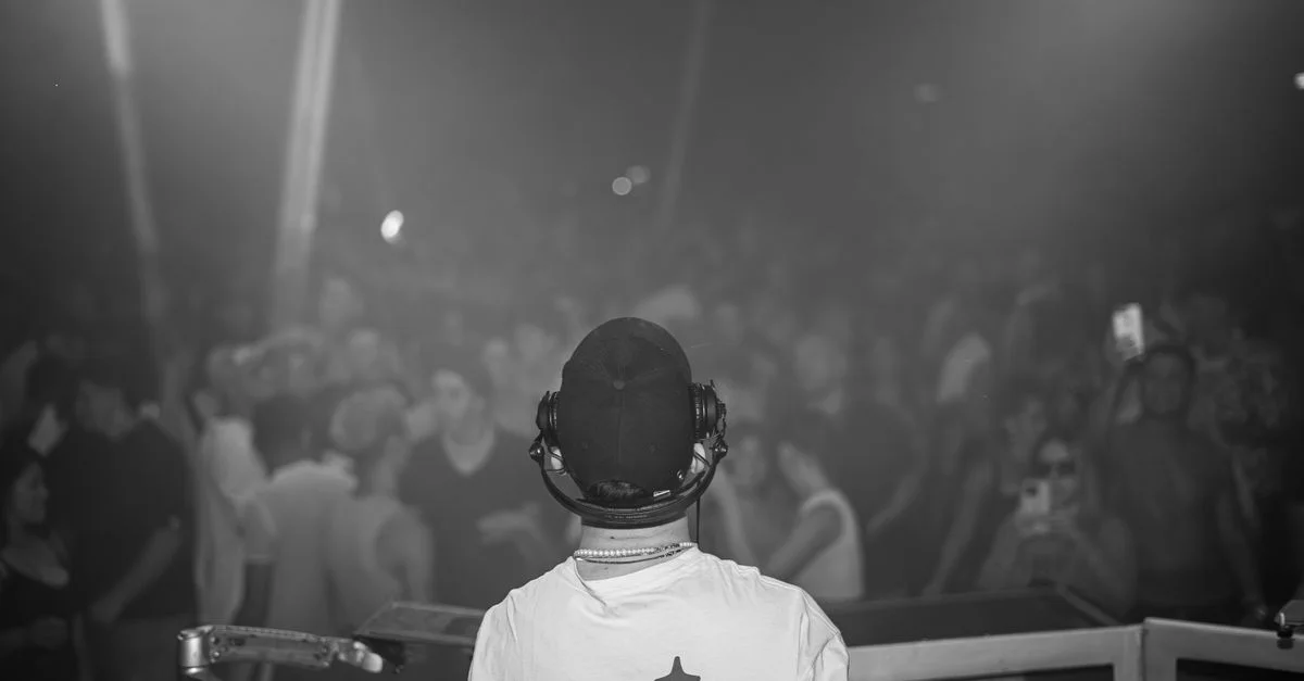 Un DJ jouant de la musique devant une foule vibrante lors d'un concert nocturne.