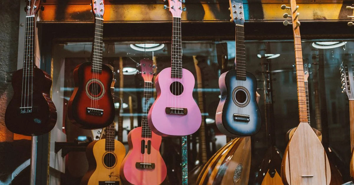 Une collection colorée d'ukulélés et de mandolines suspendus dans une vitrine de magasin de musique, rehaussant l'ambiance musicale.