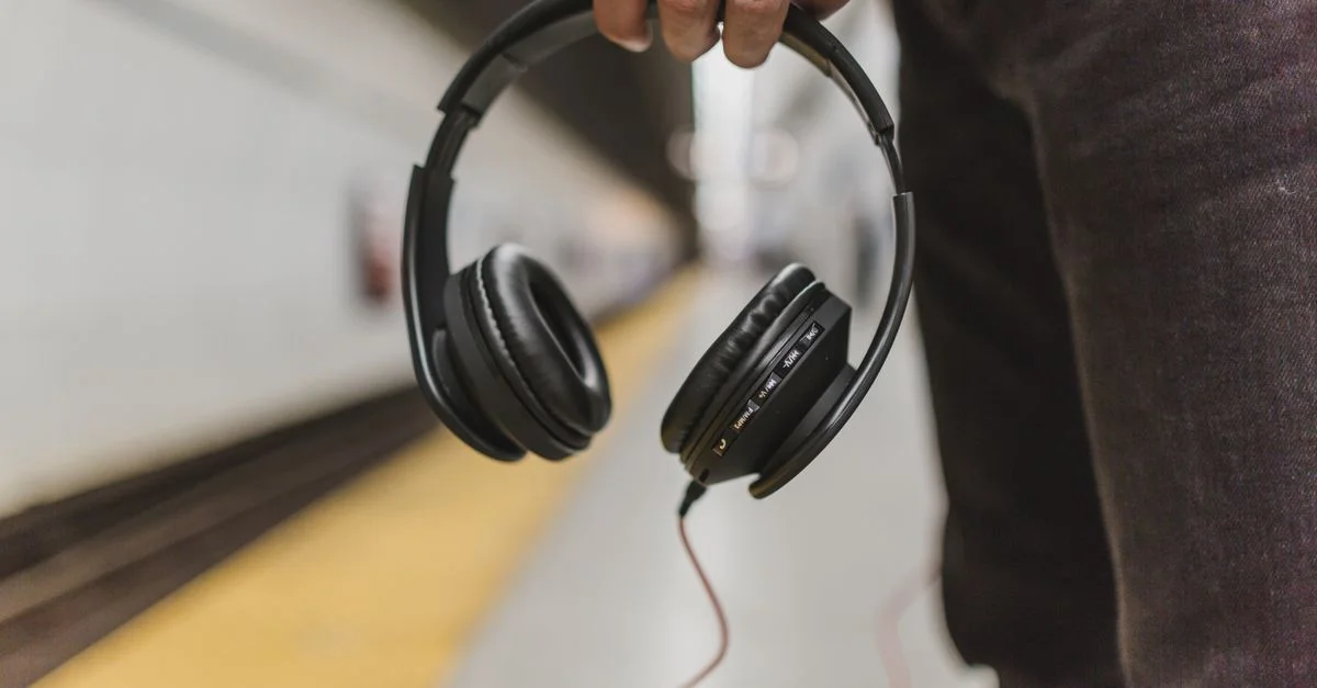 Gros plan d'une personne tenant des écouteurs dans une station de métro.