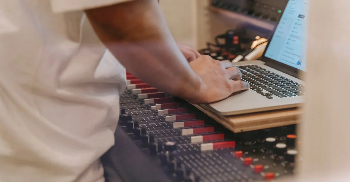 Une personne utilisant un ordinateur portable sur un mélangeur audio dans un studio d'enregistrement.