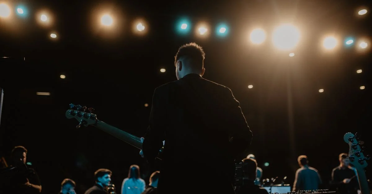 Une scène de concert nocturne captivante avec un guitariste et un groupe sur scène.