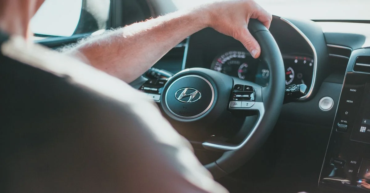 Une vue en gros plan de la main d'une personne tenant le volant d'une Hyundai à l'intérieur d'une voiture.