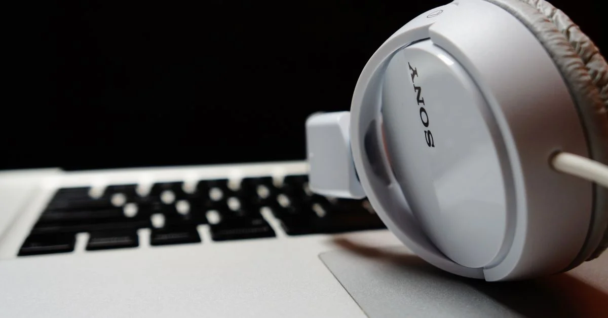 Casque blanc reposant sur un clavier d'ordinateur portable, mettant en avant la technologie moderne.
